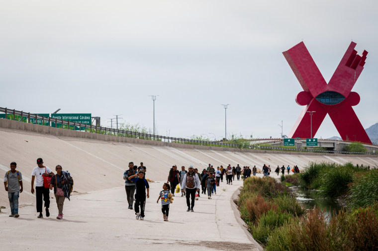 Migrants walk along the Rio Grande.