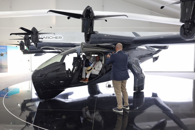 Visitors to the 2023 Dubai Air Show sit inside an Archer Aviation Midnight aircraft.