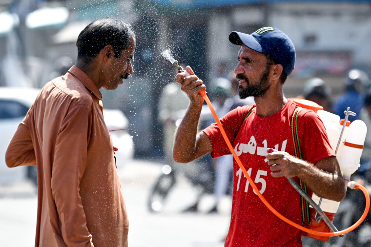 A volunteer sprays water on a bypasser's face 