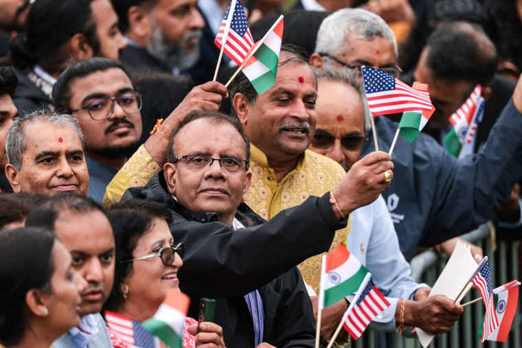 A crowd of supporters of Narendra Modi wave Indian and American flags