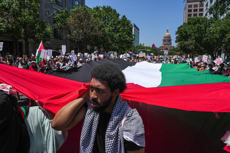 Protesters carrying a large Palestinian flag march down Congress avenue at a pro-Palestine protest in Austin, Texas