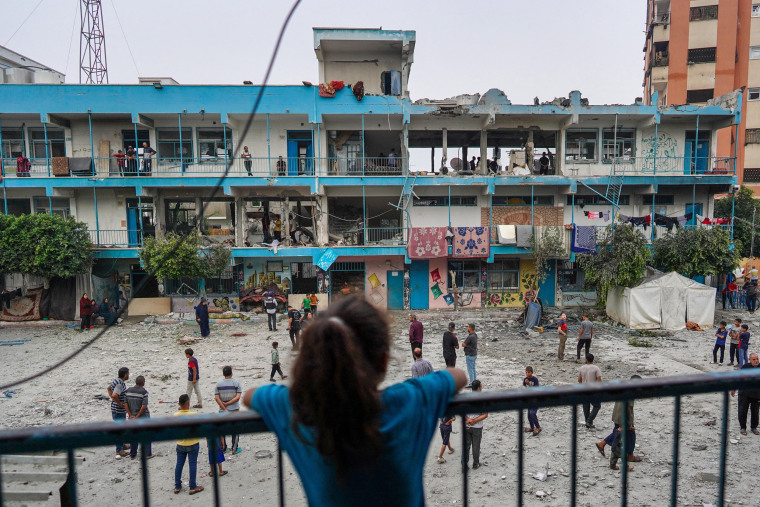 Uma menina palestina observa enquanto outras pessoas verificam uma escola da ONU que abriga pessoas deslocadas que foi atingida durante o bombardeio israelense em Nuseirat, centro de Gaza, em 6 de junho de 2024.