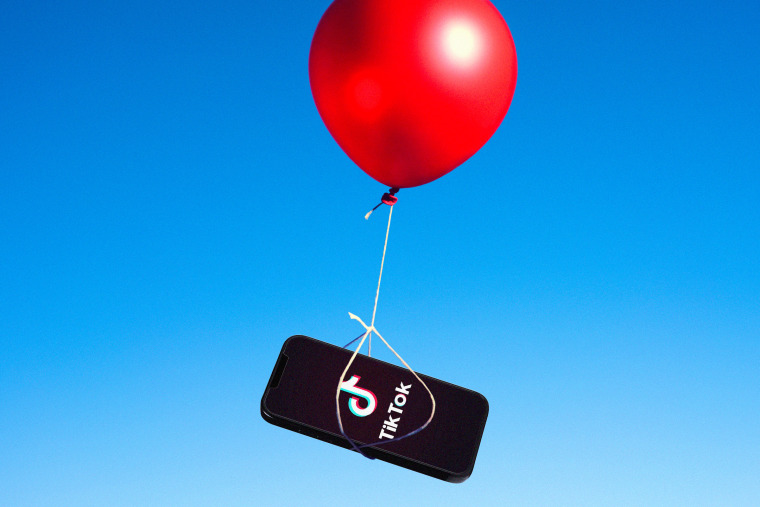 A red balloon carrying a phone with a TikTok logo on it against a blue sky