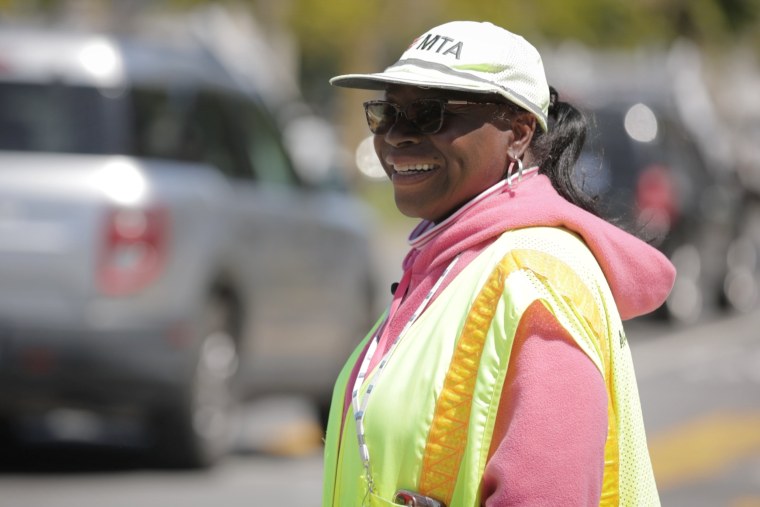 A Black woman with a yellow crossing guard vest.
