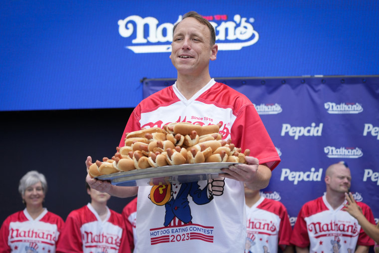 Competitive eater Joey Chestnut holds a plate of hotdogs representing his world record for eating 76 hotdogs and buns in ten minutes during a weigh-in ceremony before the Nathan's Famous July Fourth hot dog eating contest on July 3, 2023, in New York. 