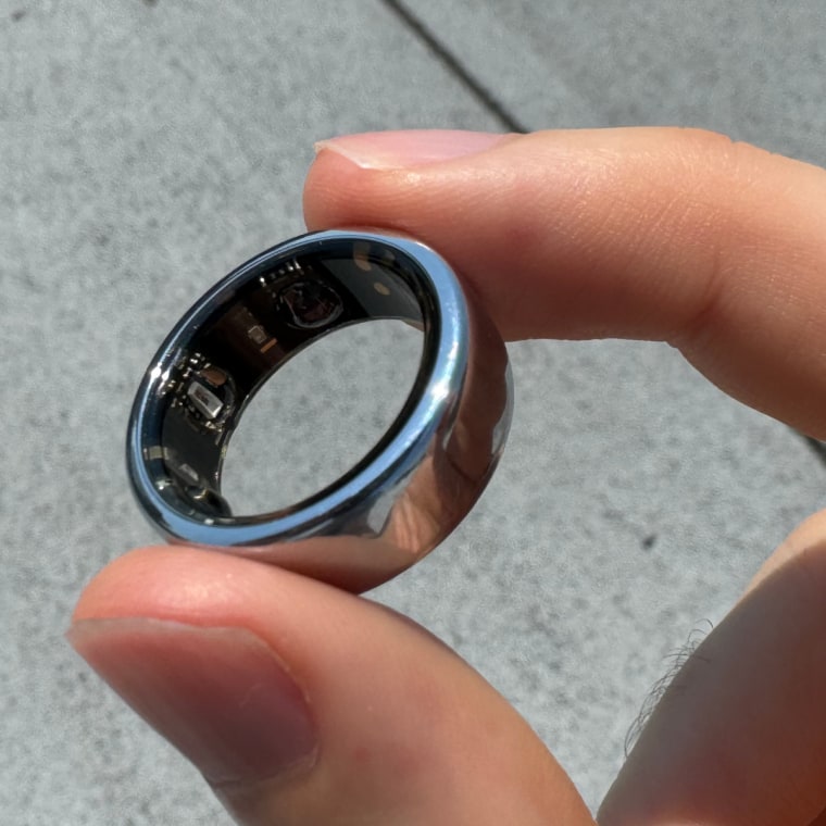 A close-up of the Oura Ring 3 between the fingers of the writer.