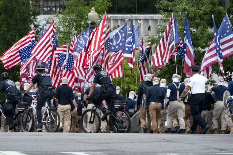 Carrying shields, covering their faces, and holding upside down U.S. flags, marchers with the Alt-Right Neo-Nazi group "Reclaim America."
