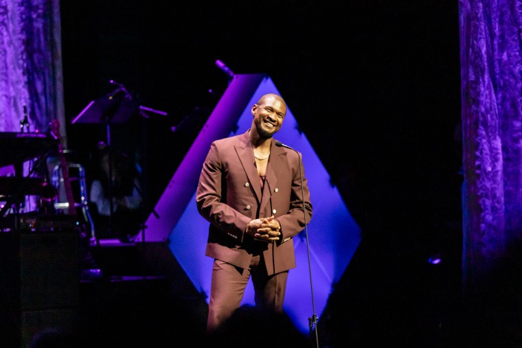 Usher on stage wearing a brown suit