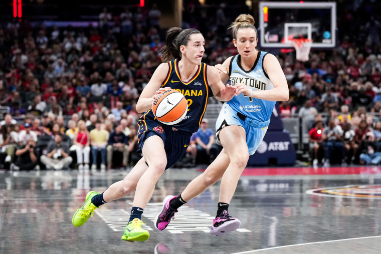 Caitlin Clark runs holding the basketball next to Marina Mabrey on the court