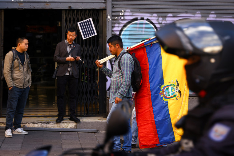 A person walks as he holds Ecuadorian flags.