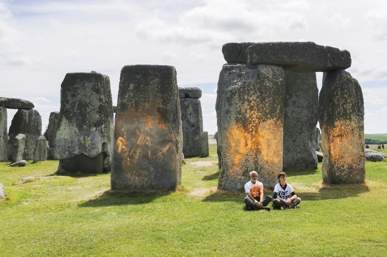 Just Stop Oil protesters sit after spraying an orange substance on Stonehenge in southwestern England on June 19, 2024.