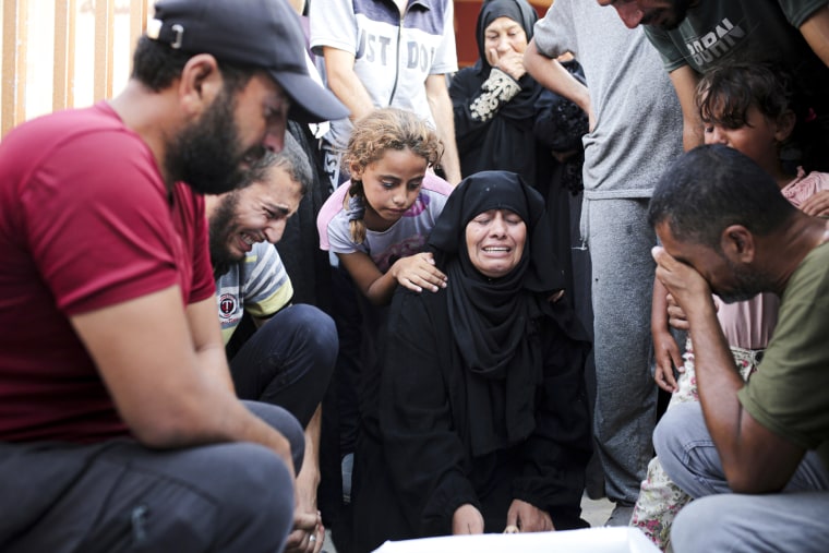 A Palestinian family kneel down and mourn a loved one killed by Israeli bombardment.