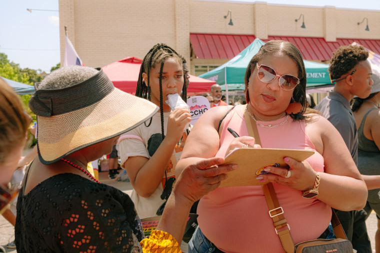A person writes on a clipboard as others watch on during the parade