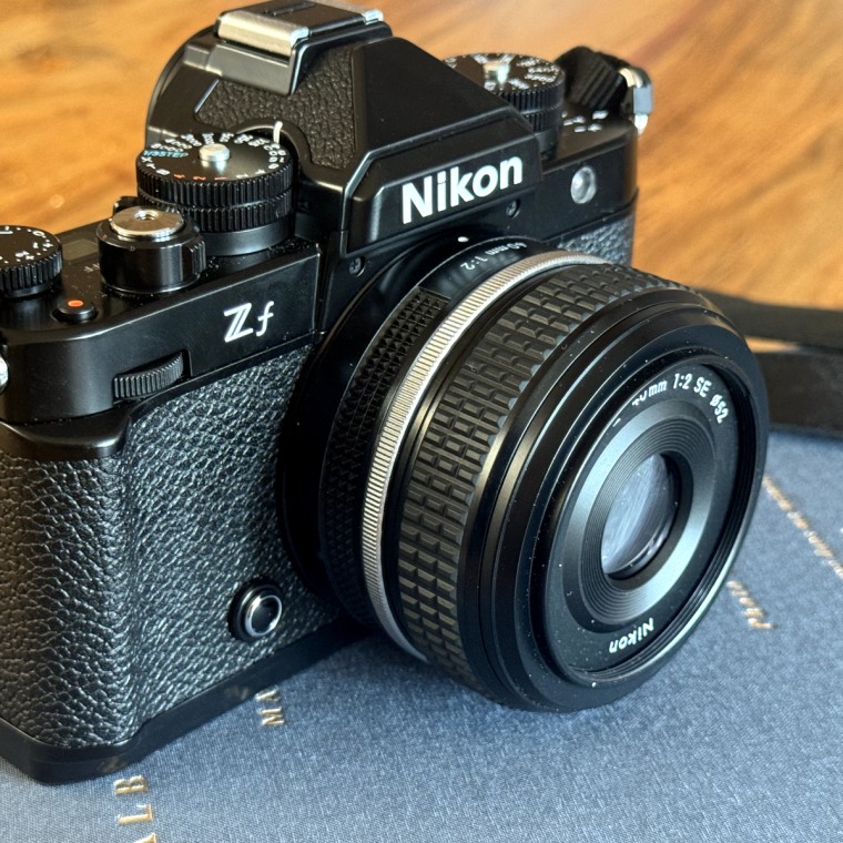 The Nikon Zf Mirrorless Camera sits on top of a table.