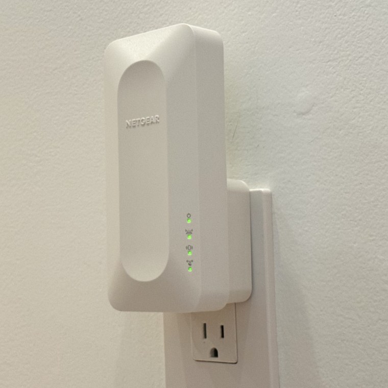 Close-up photo of the Netgear WiFi 6 Range Extender plugged into a wall outlet.