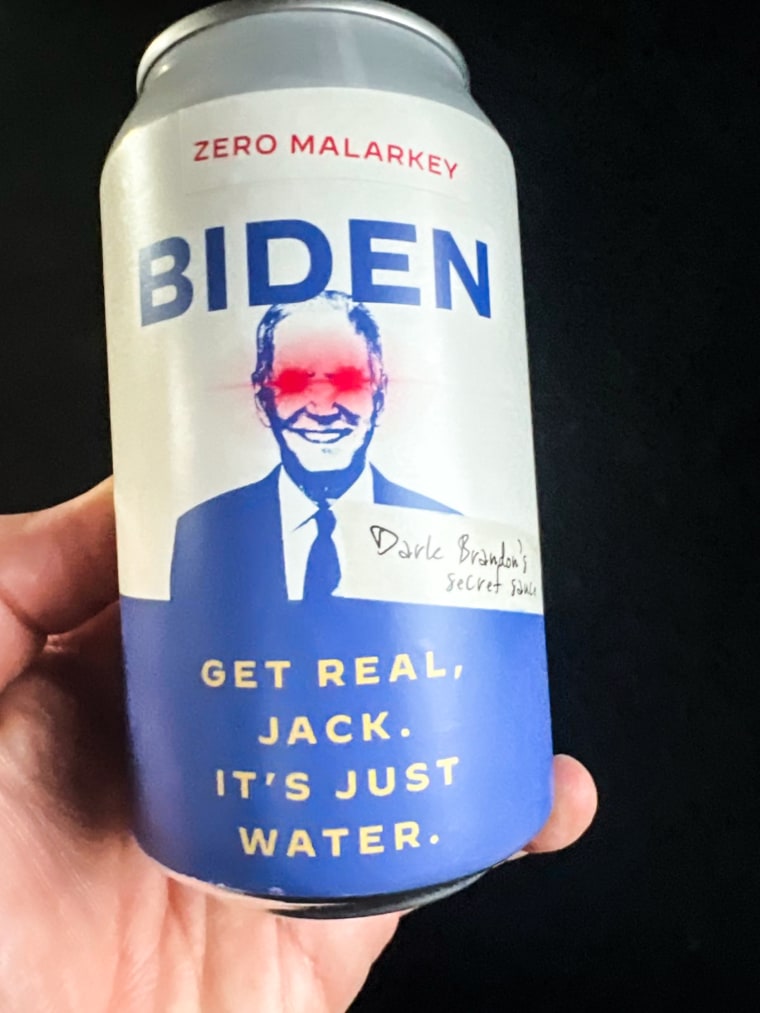 A close up of a hand holding a can of water that says "Zero malarkey. Biden. Dark Brandon's secret sauce. Get real, Jack. It's just water."