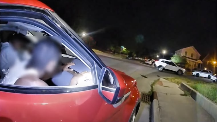 A red car with a driver and passenger are seen parked in body camera footage