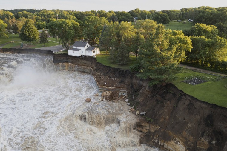 A home as it teeters before partially collapsing into the Blue Earth River at the Rapidan Dam in Mankato, Minn.