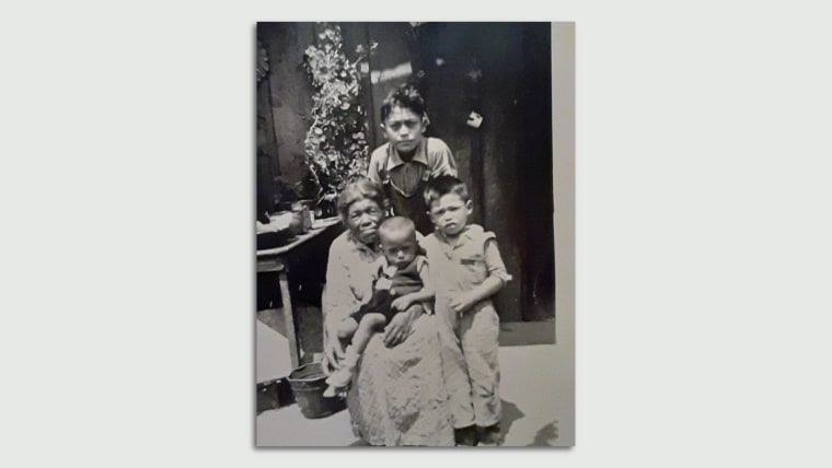 Fotografía en blanco y negro de una mujer, Francisca Martínez, posando con sus tres nietos