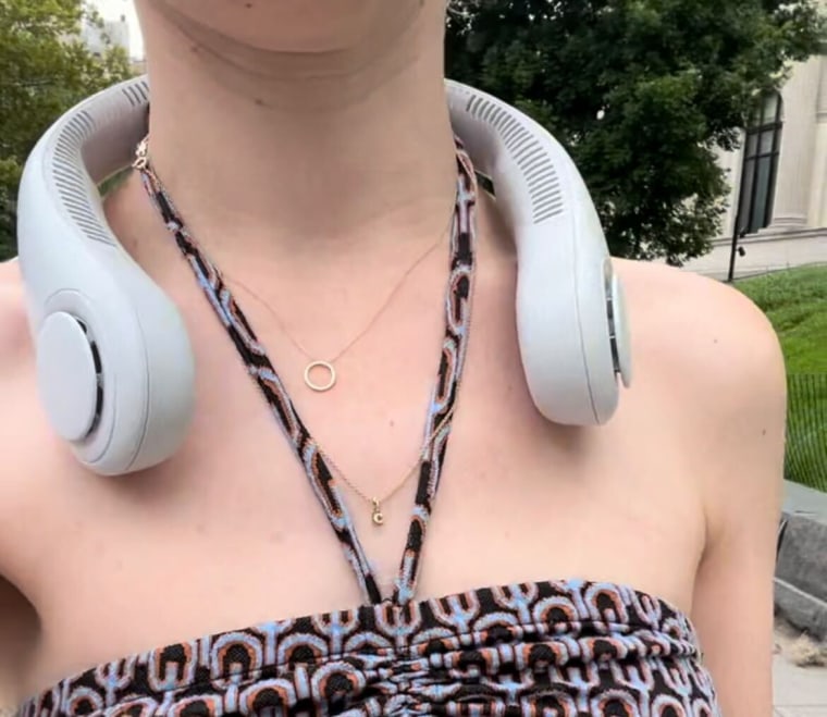 A woman wearing a white personal neck fan while walking outdoors