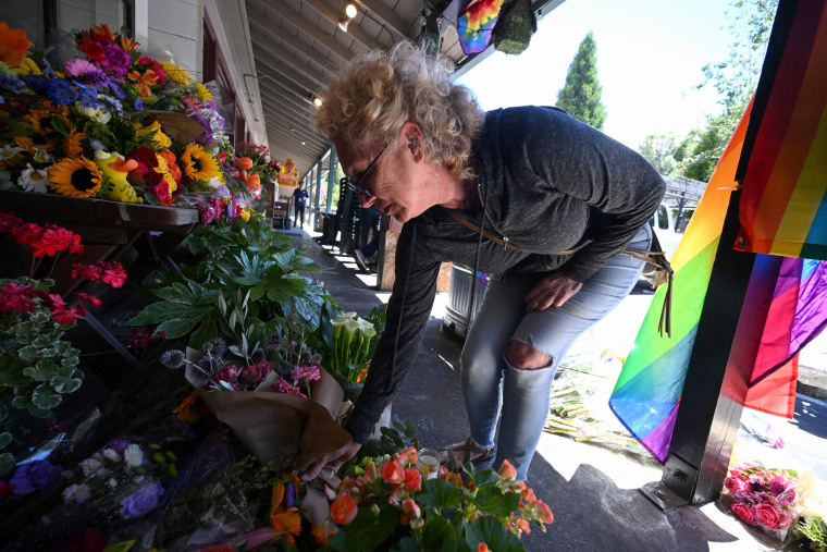 A resident leaves flowers at a makeshift memorial outside the Mag.Pi clothing store