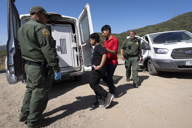 Agentes de la Patrulla Fronteriza escoltan a dos migrantes para ser transportados y procesados, el miércoles 5 de junio de 2024, cerca de Dulzura, California