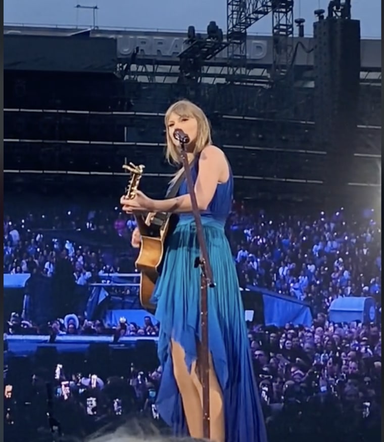 Taylor Swift uses her guitar to point into the crowd at fans waving for help.