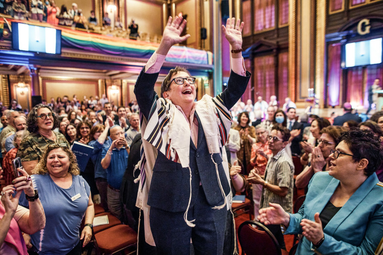 Sharon Kleinbaum sings and raises up her hands in a packed synagogue