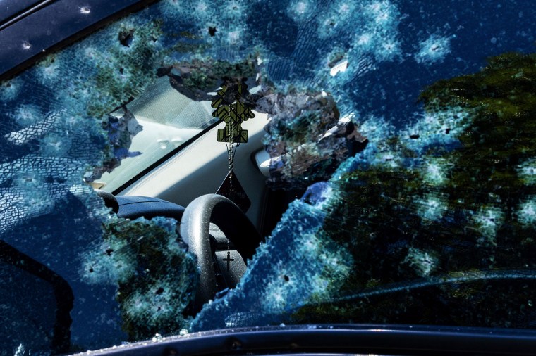 A rosary is seen through a damaged vehicle window