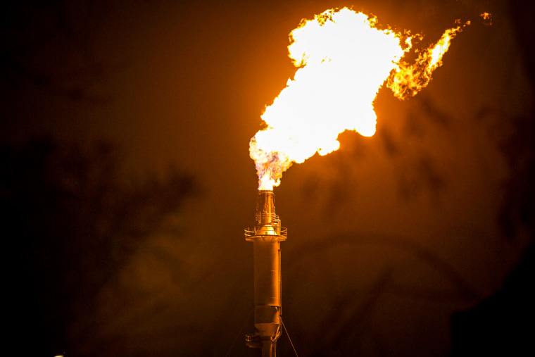 Flames shoot from a refinery tower.