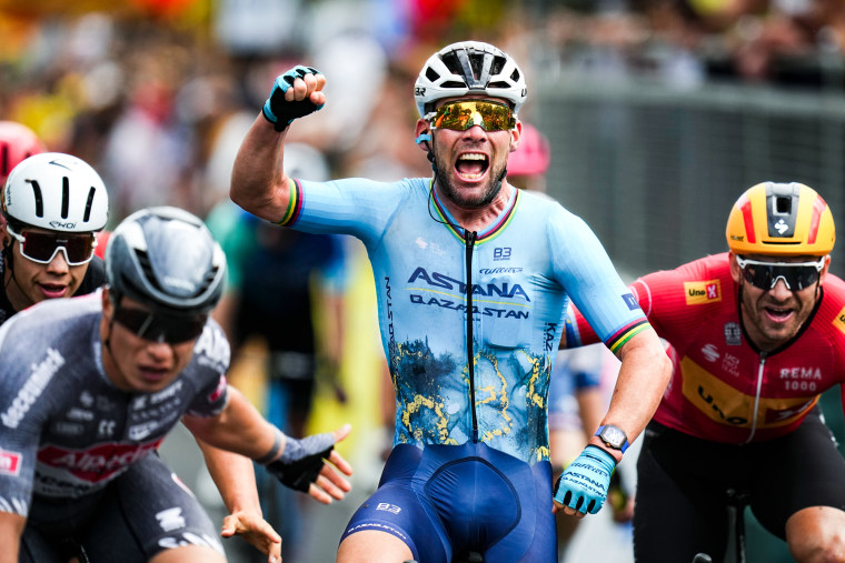 Mark Cavendish crosses the finish line and raises a fist in the air