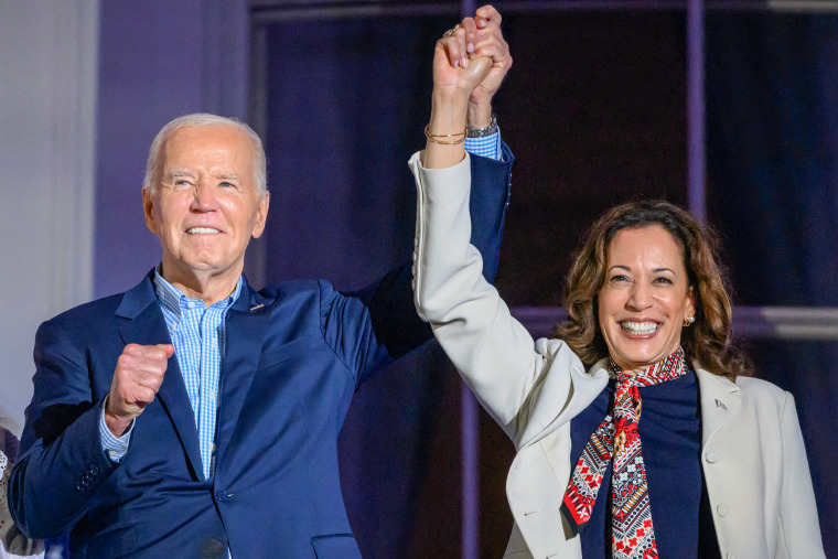 Joe Biden and Kamala Harris hold hands and gesture.