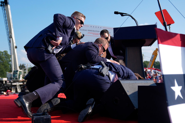 Donald Trump is covered by U.S. Secret Service agents at a campaign rally Saturday.