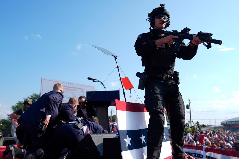 Secret Service agents cover Donald Trump. 