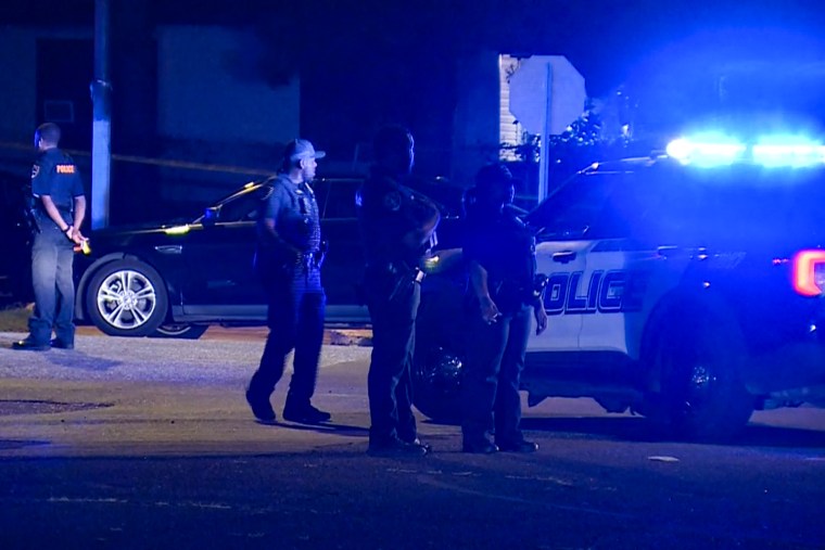 Police officers and cars on the scene outside at night