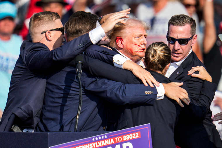 Donald Trump, with a bloodied ear, is escorted off stage by secret service agents