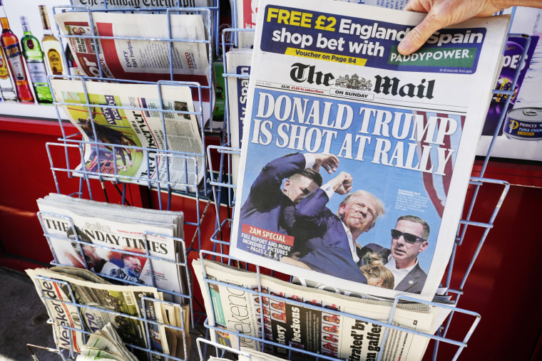 Uma mulher compra um exemplar do jornal British Mail on Sunday com reportagem sobre Donald Trump sendo baleado em um comício.