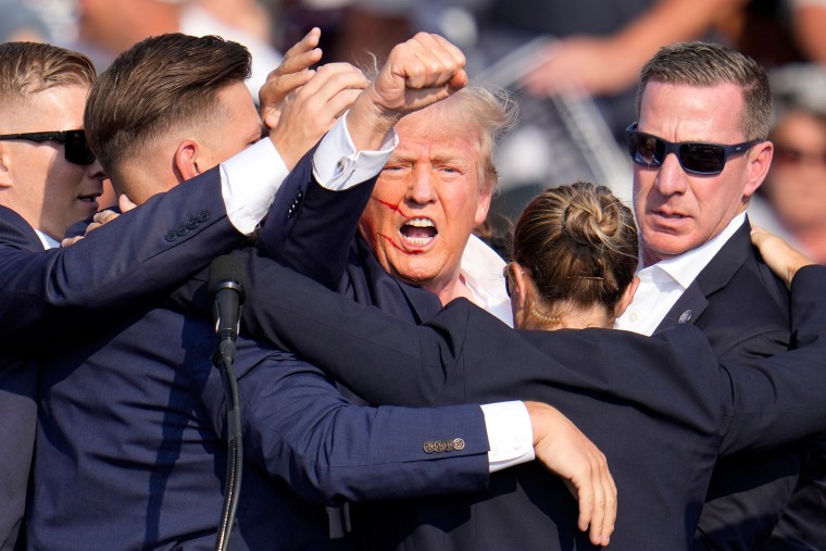 U.S. Secret Service agents hold Trump as he pumps his fist