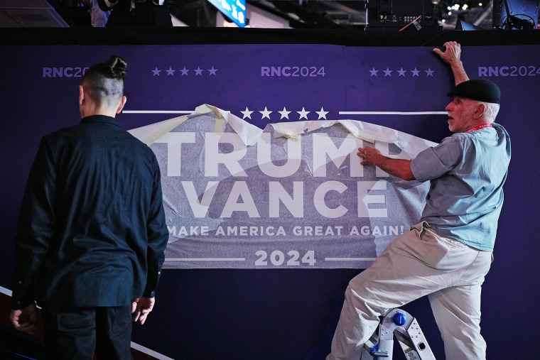 Workers place a Trump-Vance campaign sign at the Republican National Convention on July 16, 2024 in Milwaukee.