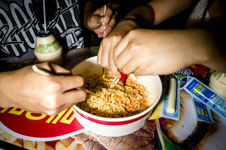 Tourists mix a bowl of instant noodles.