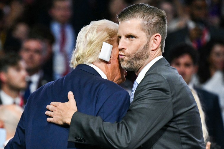 Eric Trump dan Donald Trump berpelukan, perban terlihat di telinga Trump