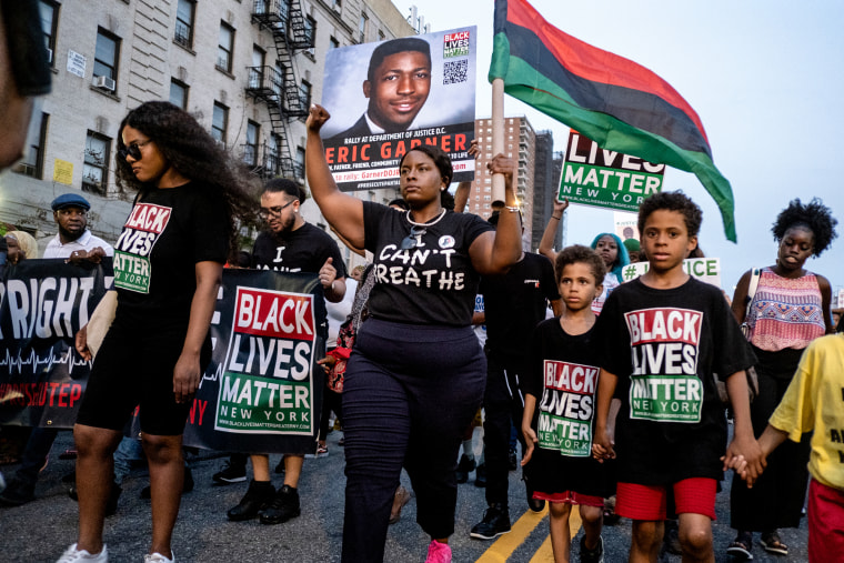 Activists with Black Lives Matter protest on the street, holding a picture of Eric Garner