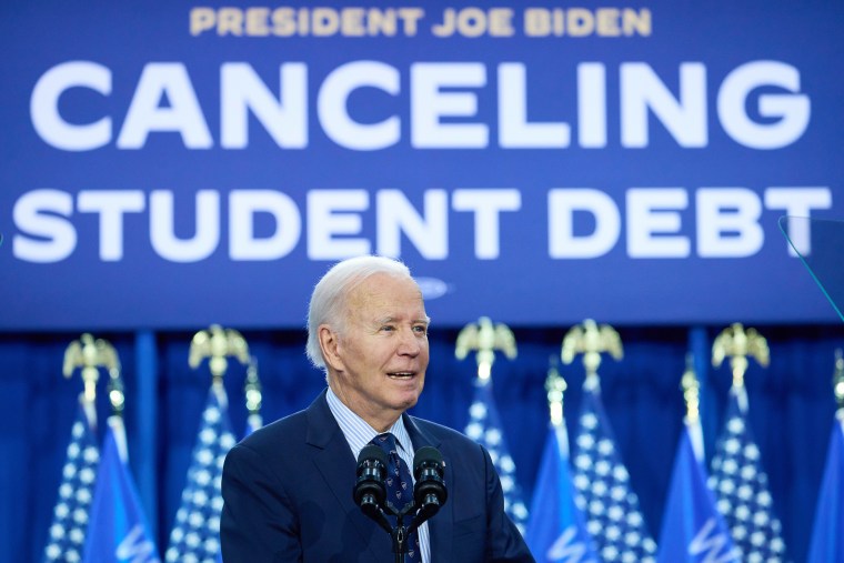  Joe Biden speaks in front of a sign that reads "President Joe Biden Cancelling Student Debt"