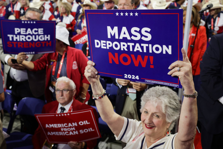 As pessoas seguram "Deportação em massa já!" cartazes na Convenção Nacional Republicana em Milwaukee