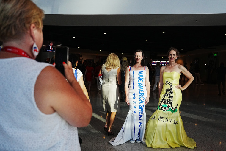 A woman takes a photo of attendees in gowns 