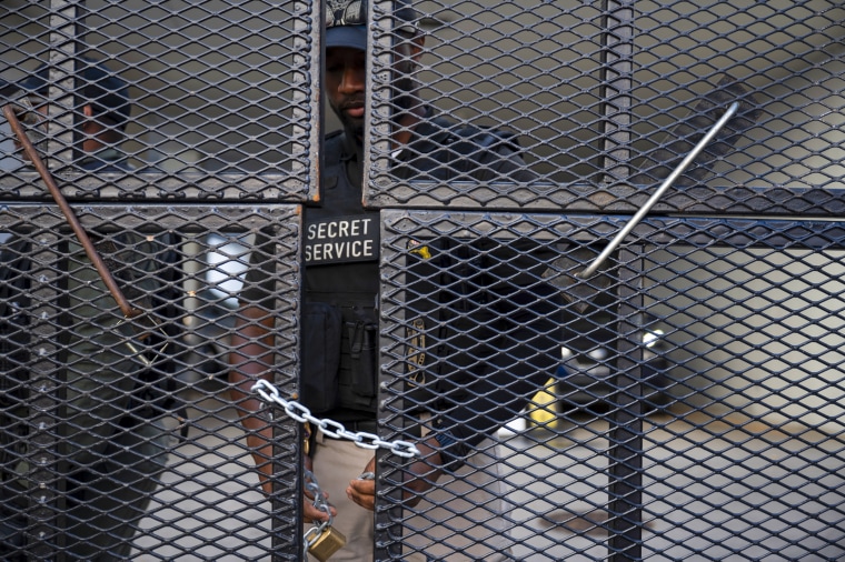 A secret service officer attaches a chain and lock to the security perimeter fence.