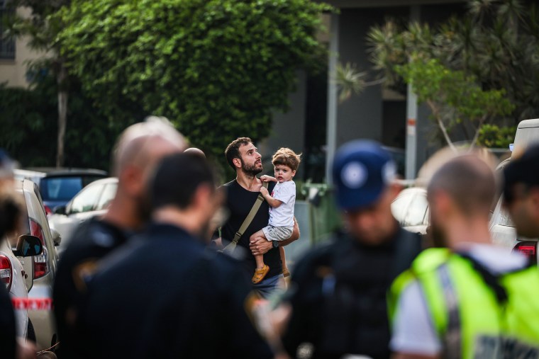 Um homem carrega uma criança perto do local de uma explosão em Tel Aviv em 19 de julho de 2024.