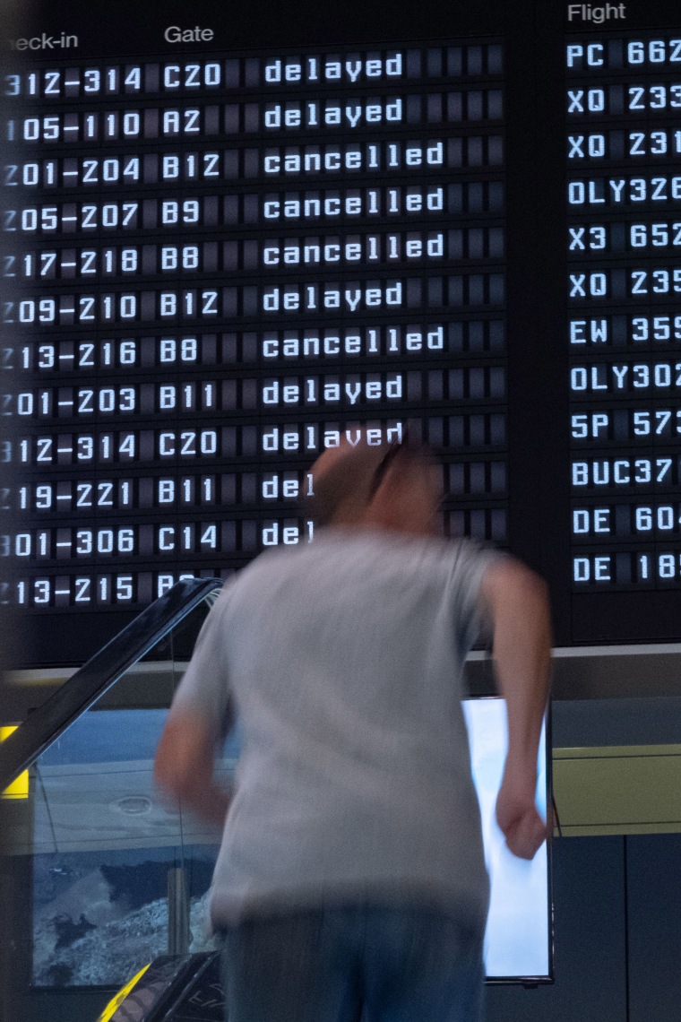 A person on an escalator in front of screen with delays and cancellations