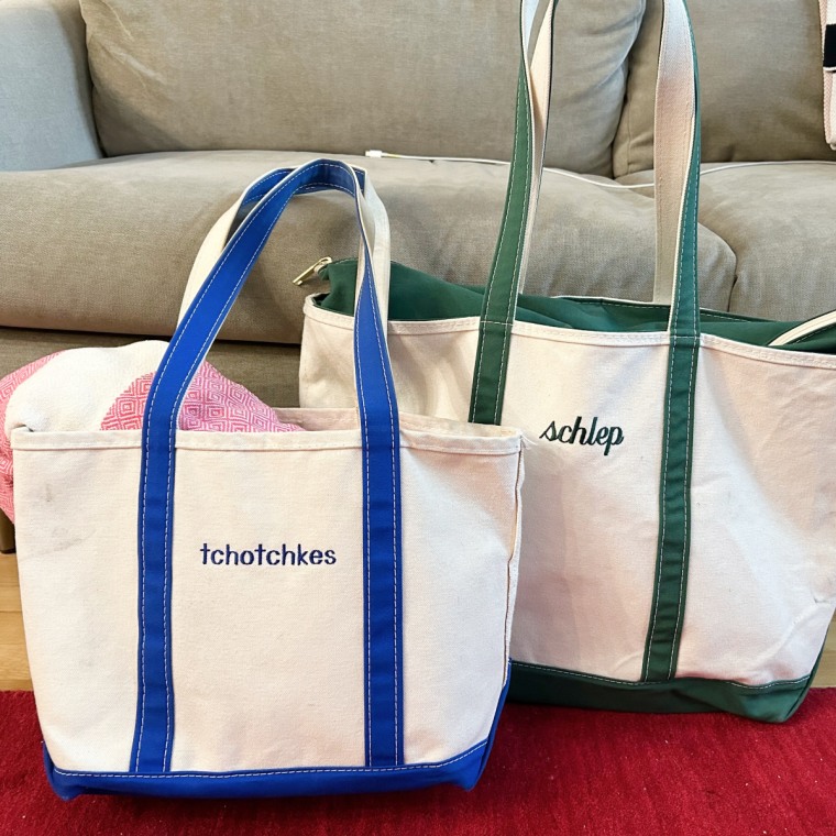 Close-up of a medium blue lined and a large green lined L.L. Bean Boat and Tote bag in front of a bookshelf.