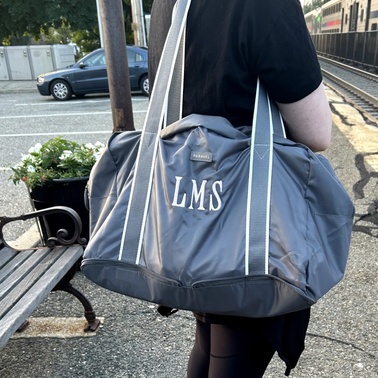 Lindsay Schneider wearing her monogrammed flatiron gray Paravel Fold-Up bag on her shoulder.